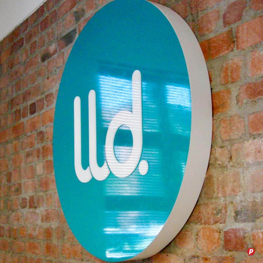Modern blue circular sign with "lld." logo on brick wall background.