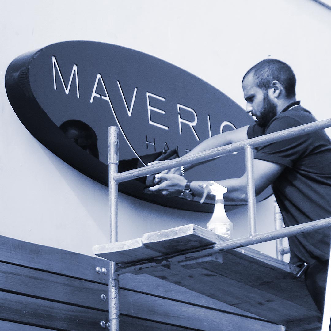 Maverick Hair Salon sign being installed by a technician in a salon setting.