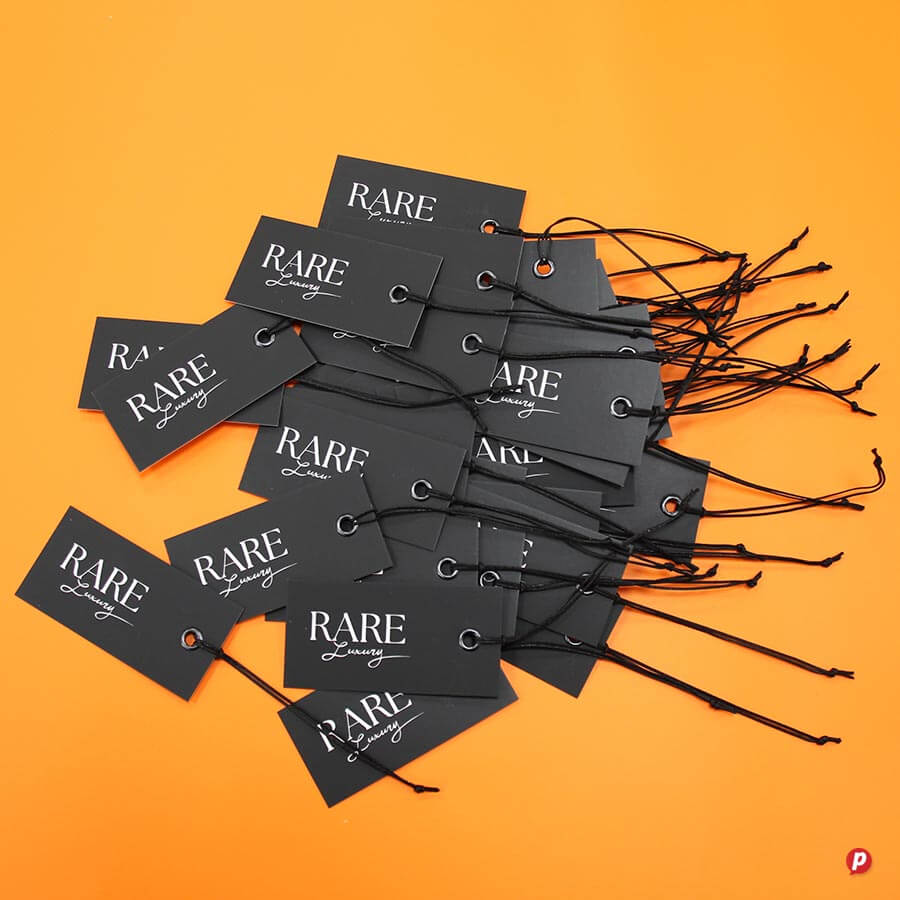 Black clothing tags with "RARE" branding on an orange background, showcasing fashion accessories or.